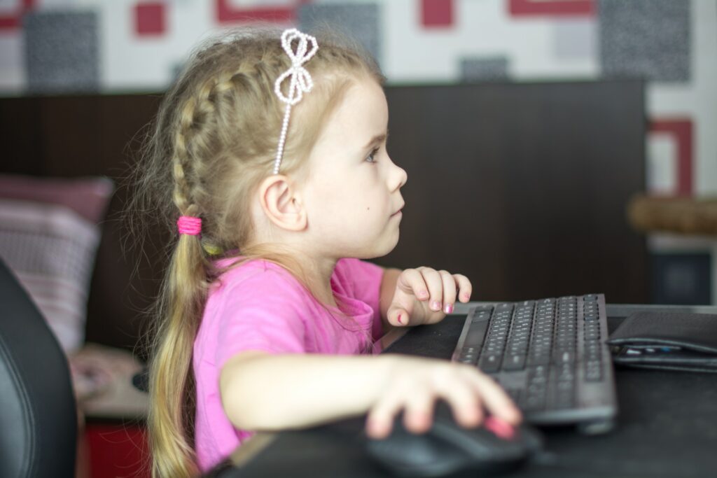 Une enfant sur un bureau travaille sur un écran.