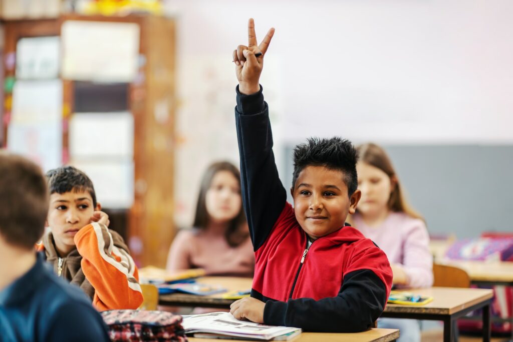 Un écolier lève le doigt pour répondre à une question.