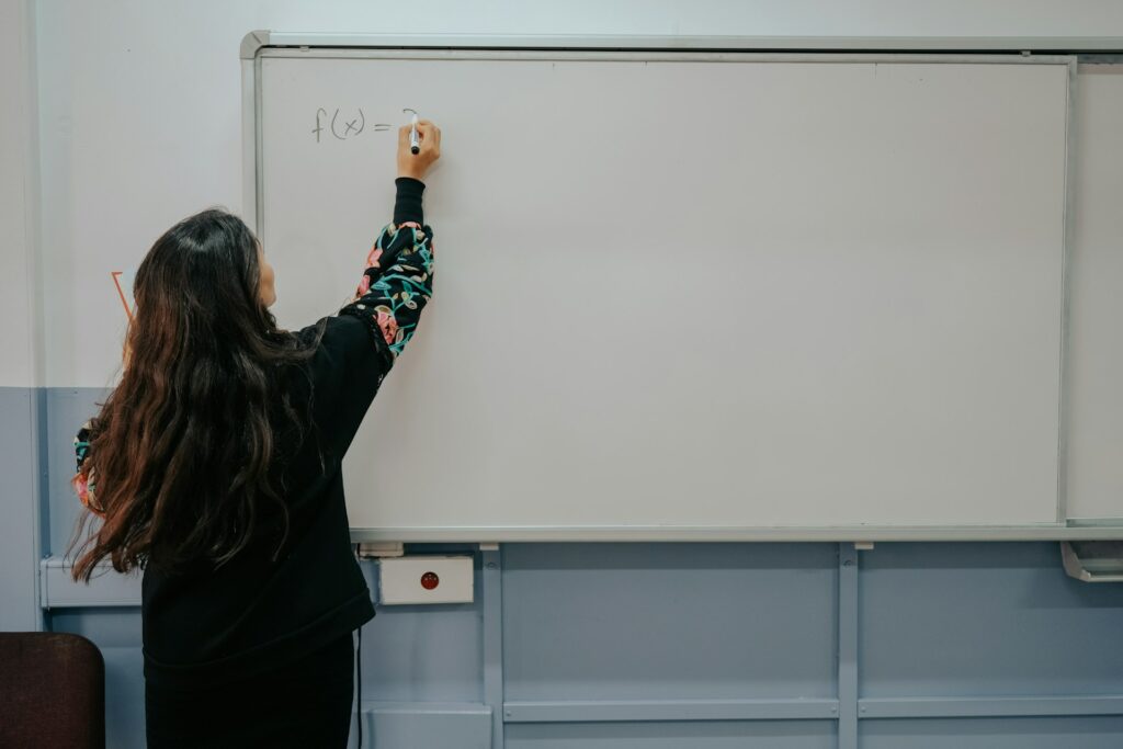 Une femme écrit sur un tableau dans une salle de classe.