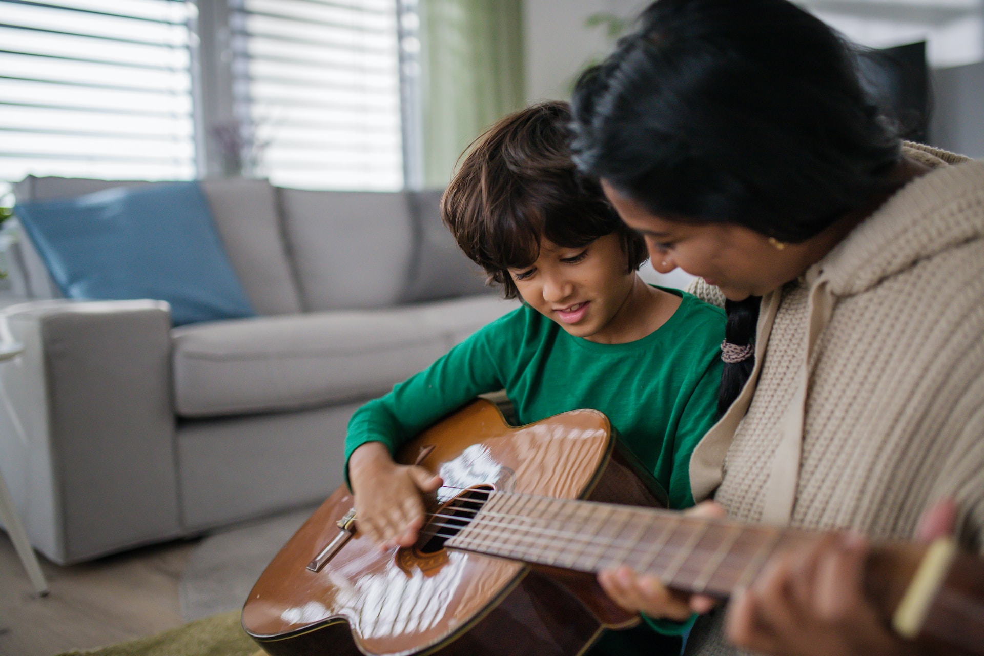 Une enfant prend un cours de musique avec une prof à la maison.