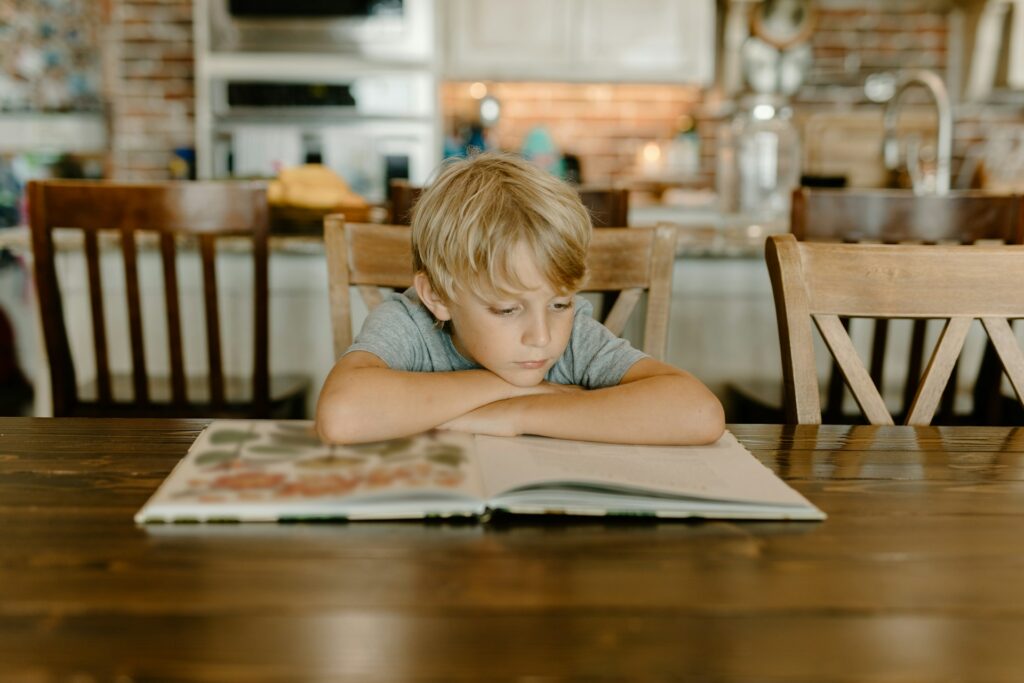 Un petit en train de lire dans une cuisine.