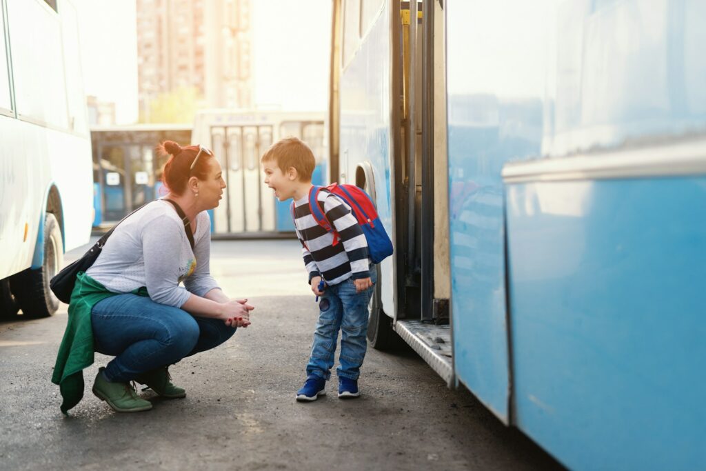 Un garçon discute avec un adulte devant la porte d'un bus.