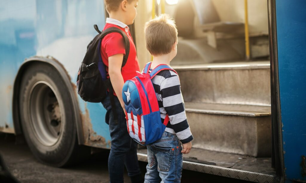 Deux garçons montent dans un bus pour aller à l'école.