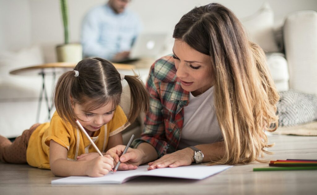 Une maman avec sa fille semble l'aider à faire ses devoirs.