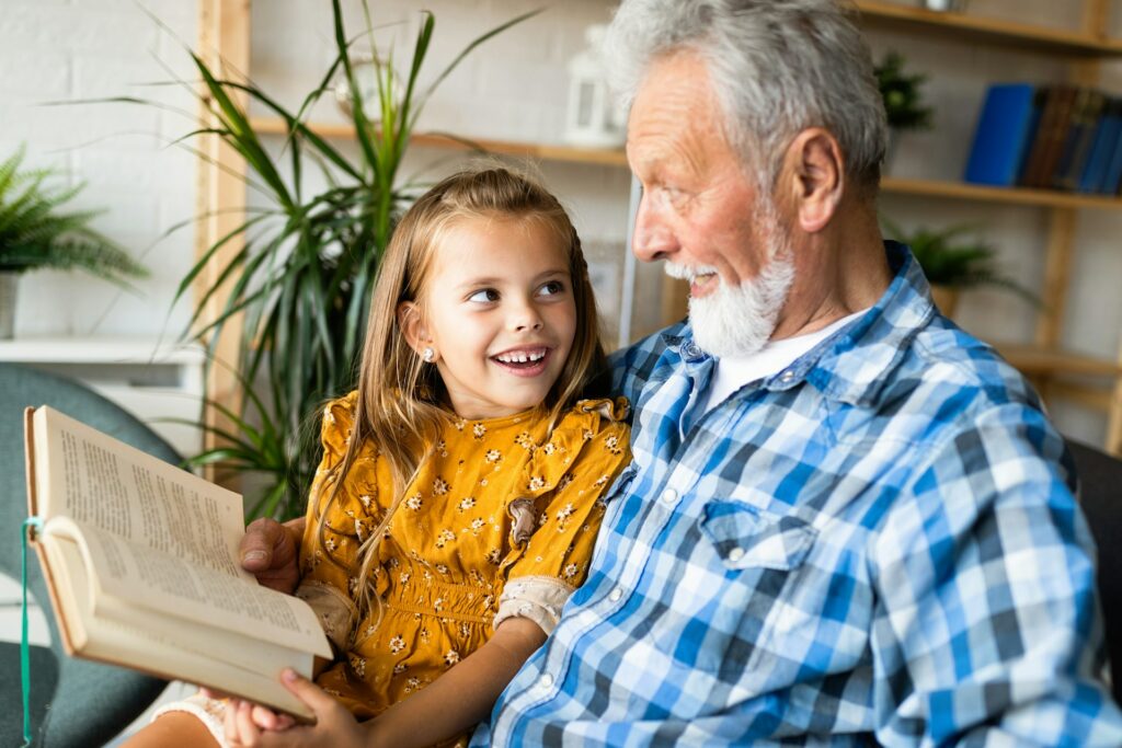 Un homme assez vieux donne un cours de lecture à une enfant.