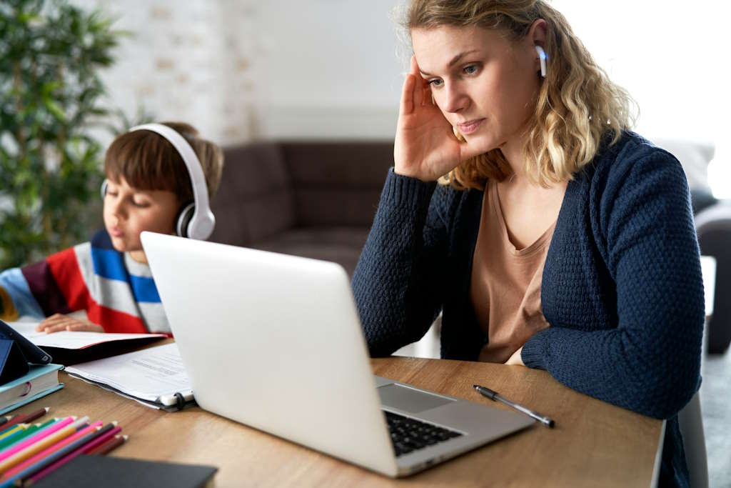 Une maman devant l'ordinateur à côté de son fils.