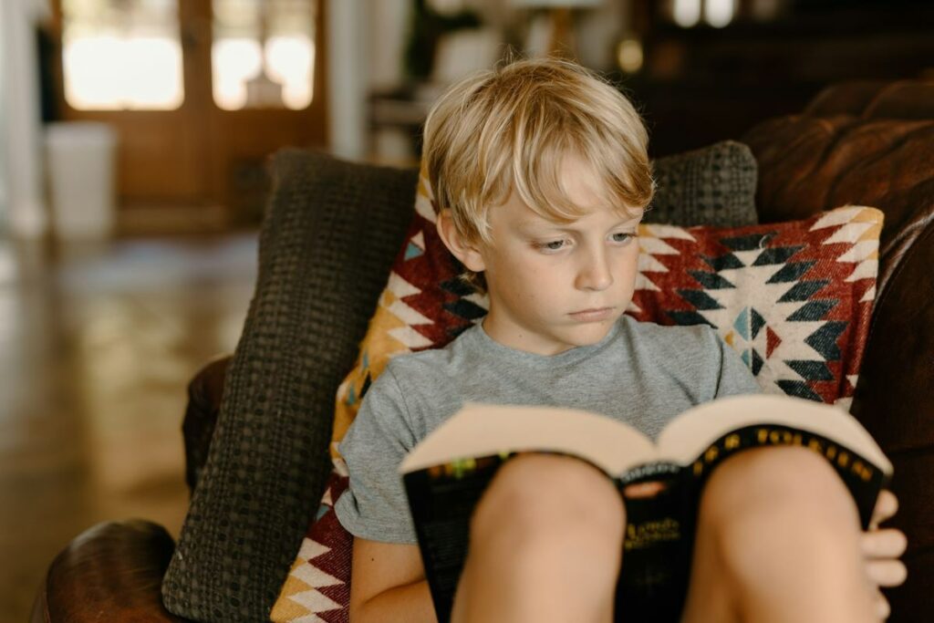 Un petit enfant en train de lire un roman sur ses genoux.
