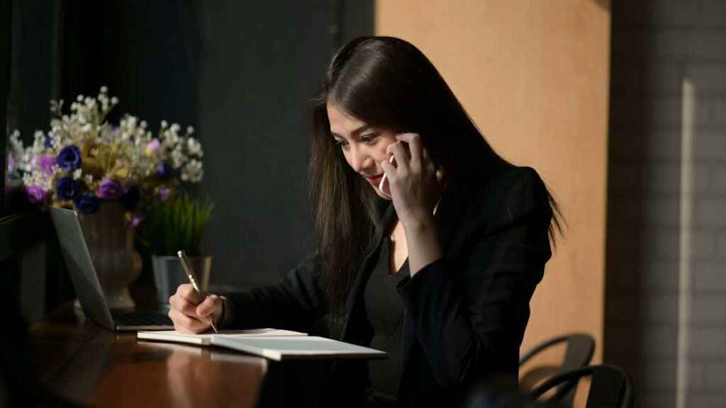 Une étudiante travaille sur une feuille de papier, sur une table sombre.