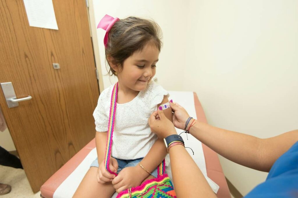 Un médecin met un pansement à une enfant après une piqûre ou un vaccin.