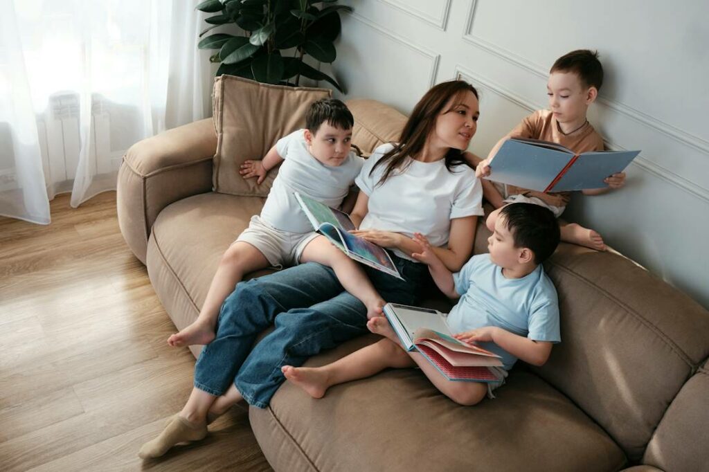 Une femme avec 3 garçons lisent un livre sur un canapé.