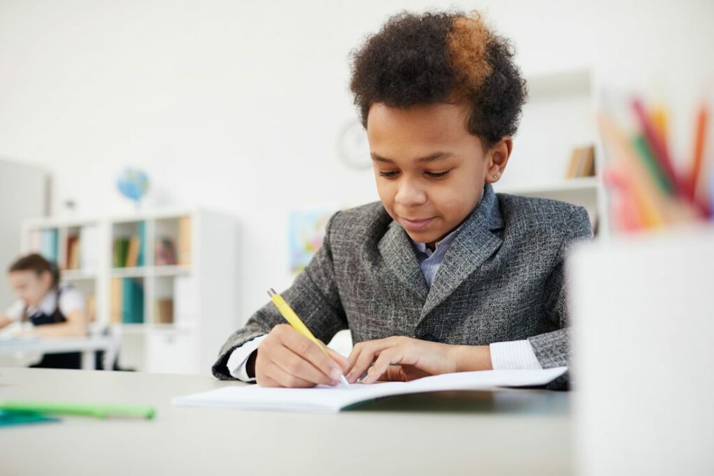 Un élève en train d'écrire à l'école, dans une salle de classe.