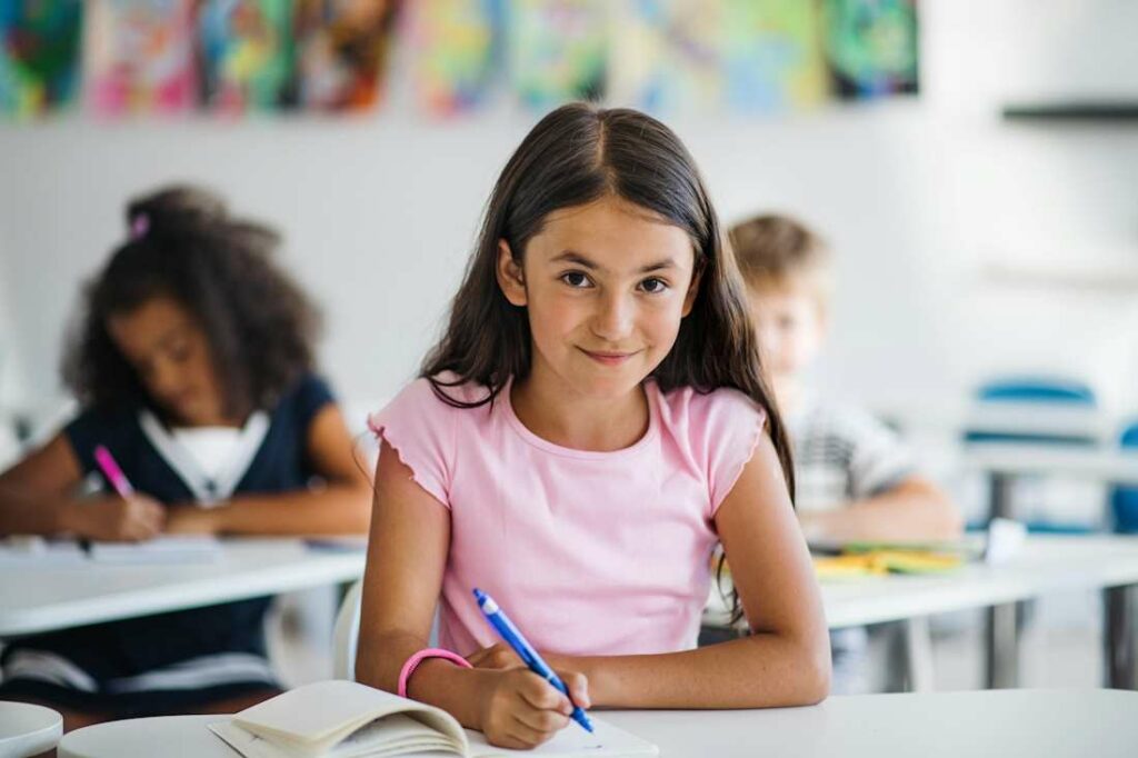 Portrait d'une petite fille de collège, heureuse d'être en cours.