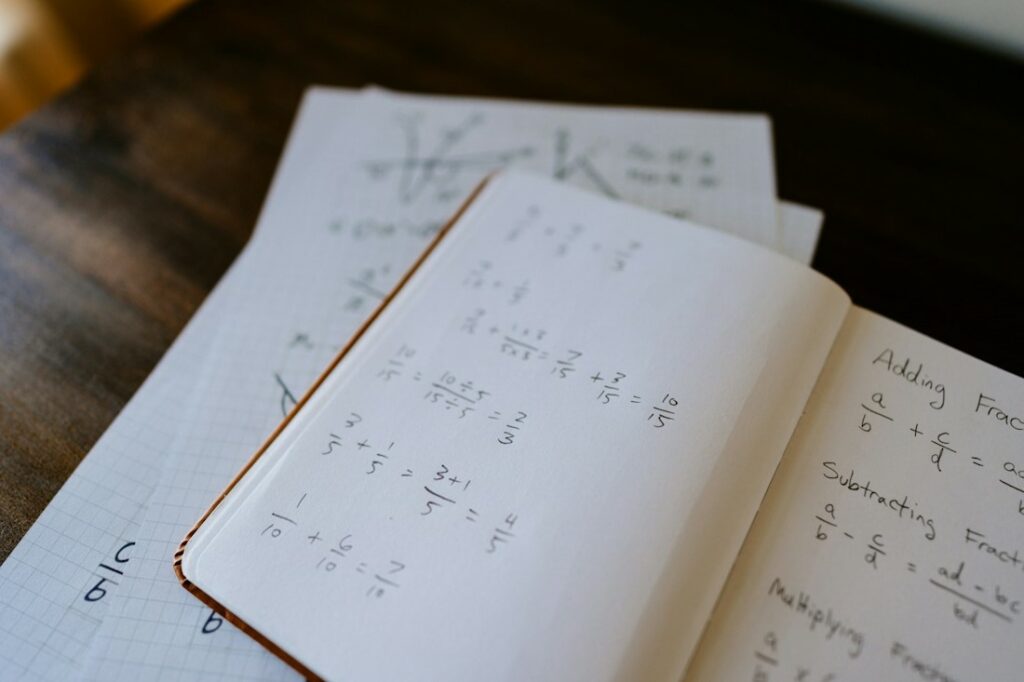 Un cahier ouvert avec des divisions et des fractions à calculer.