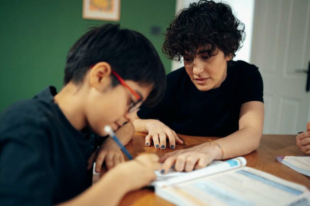 Un adolescent et un enfant travaillent ensemble avec un manuel scolaire.