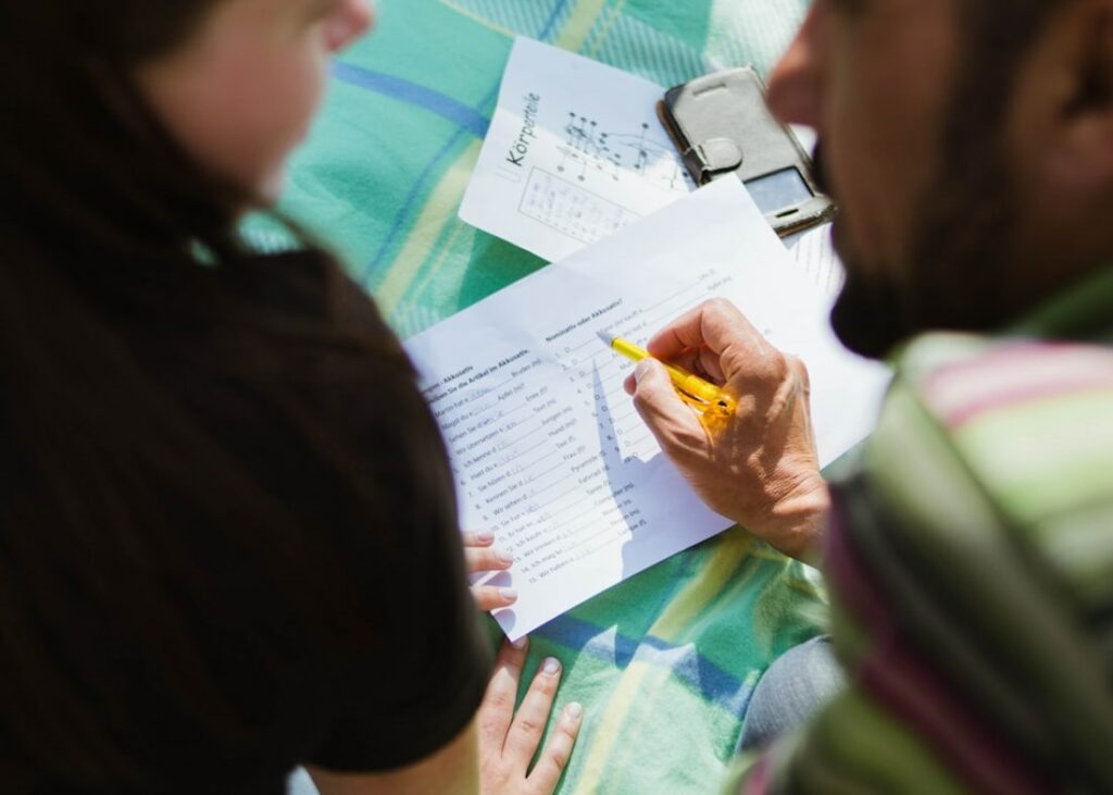 Un adulte et une personne plus jeune travaillent sur un exercice sur une feuille de papier.