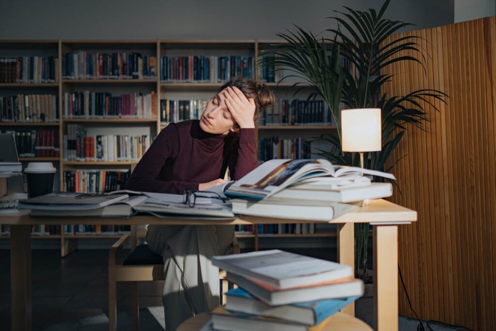 Une fille semble fatiguée avec beaucoup d'ouvrages posés sur une table.