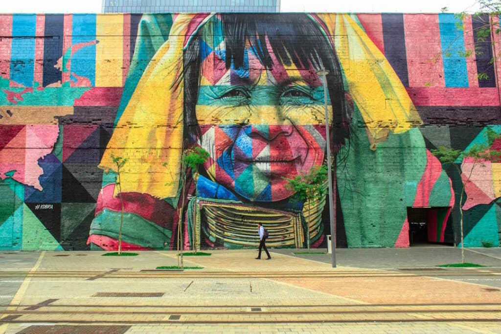 Peinture géante d'une femme sur une façade en milieu urbain.