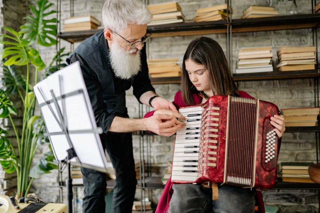 Un professeur musicien montre à une jeune fille où jouer une note d'accordéon.