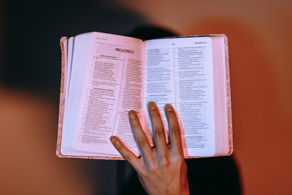 Vue sur un livre ouvert, tenu par une main gauche.