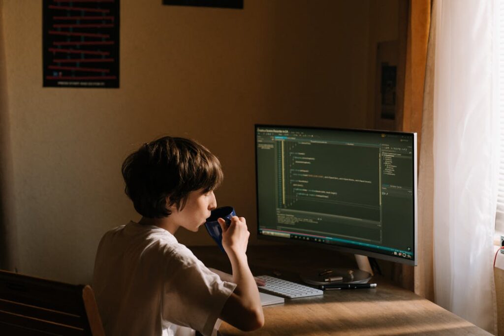 Un jeune élève travaille devant un écran sur une feuille de code informatique.