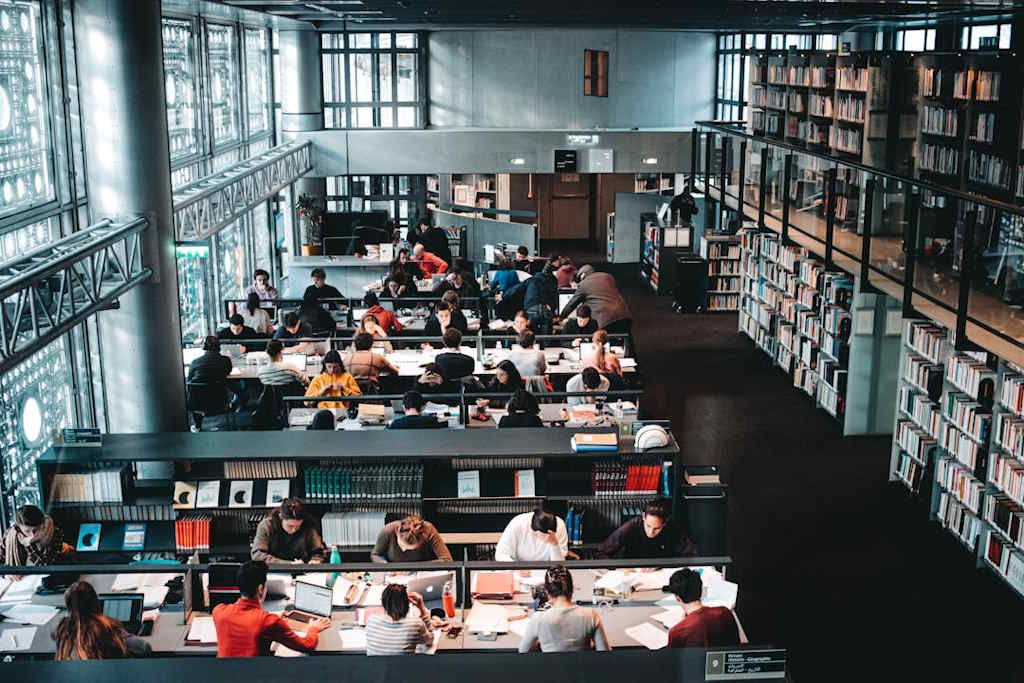 Vue d'une salle de bibliothèque avec de nombreuses personnes en train de lire et de travailler.