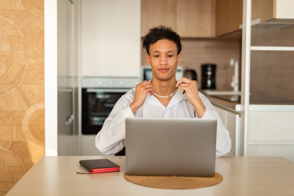 Un homme en chemise blanche devant un écran de labtop.