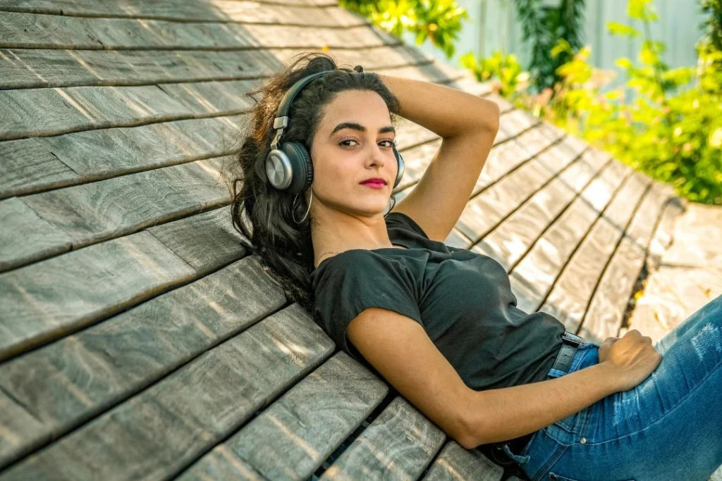 Une jolie jeune femme est adossée à un toit en pente en écoutant de la musique.