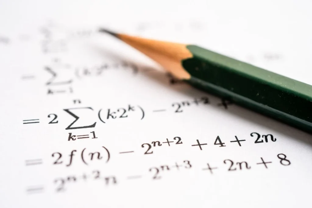 Un crayon à papier sur une feuille avec des équations mathématiques.