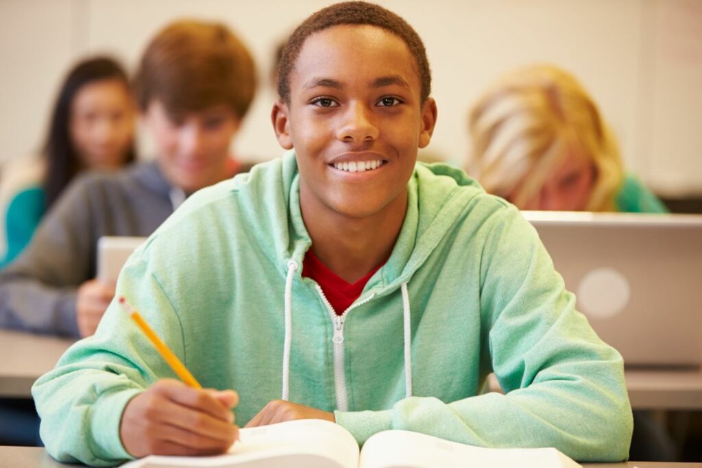 Un élève souriant en train de passer un examen en classe.