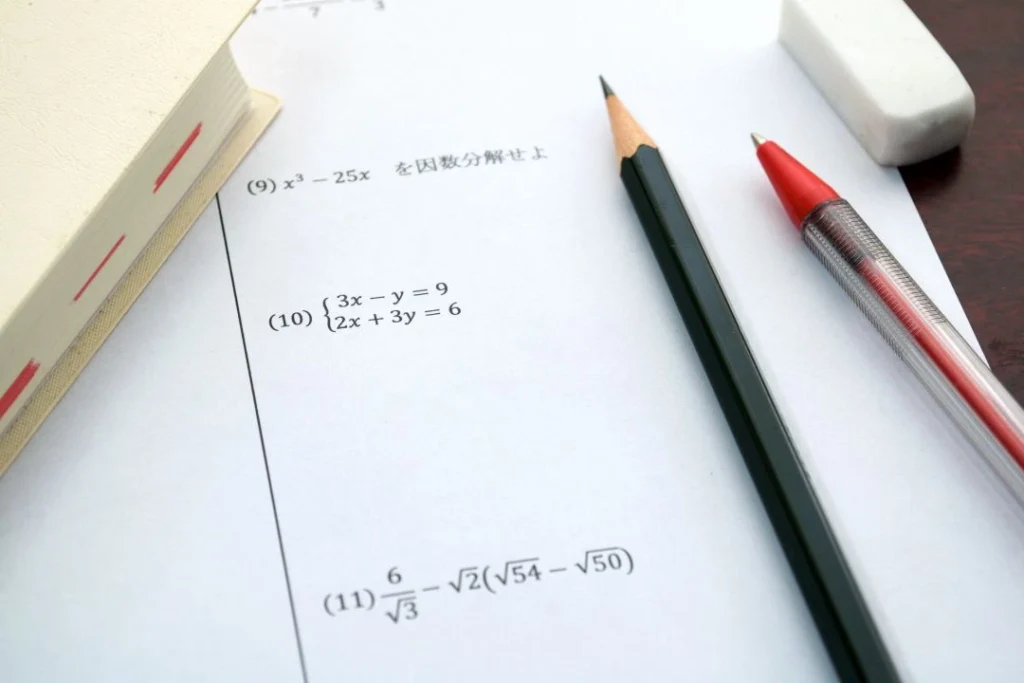 Une feuille qui semble être un sujet de maths avec des crayons.