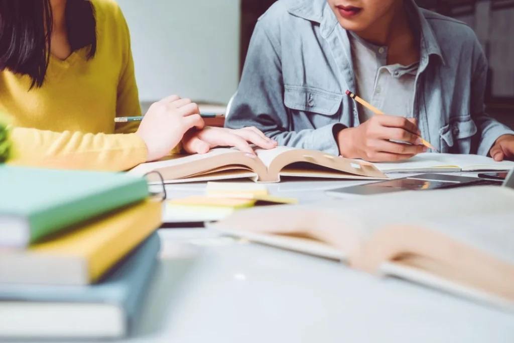 Des étudiants travaillent sur une table avec des manuels scolaires.