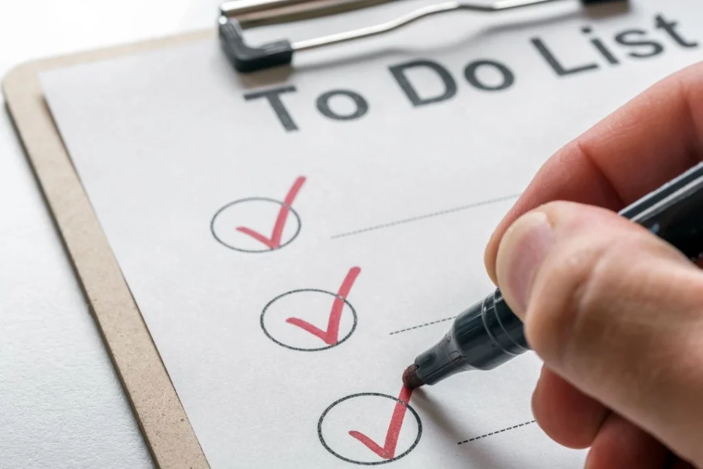 Une main droite coche une checklist pour suivre l'avancement de ses projets.
