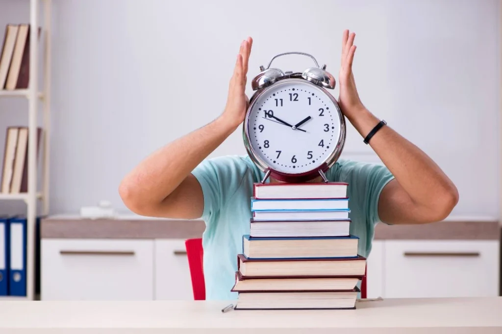 Une horloge posée sur une pile d'ouvrages, tenue par deux mains.