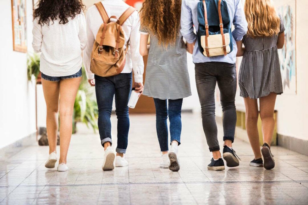 Des adolescents marchent dans un couloir d'un établissement scolaire.