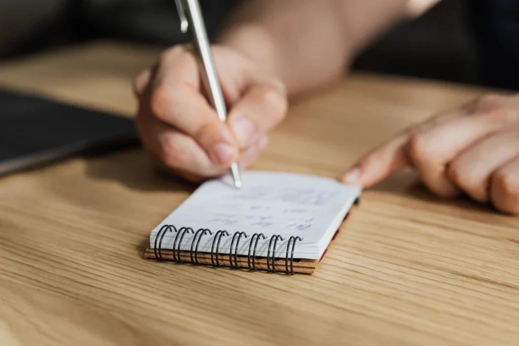 Une personne est en train de faire des annotations sur un petit carnet.