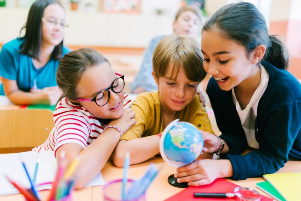 Des enfants en train d'étudier une mappemonde.