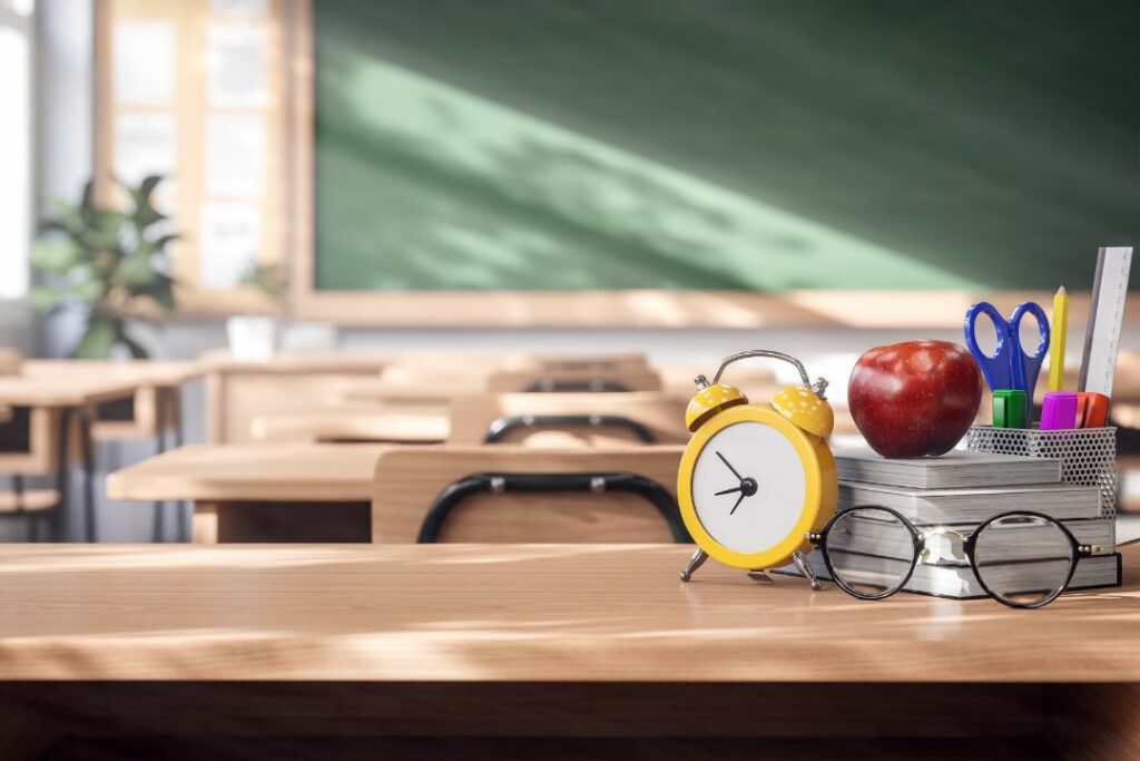 Vue des tables et des chaises vides dans une classe avec un tableau vert au fond.