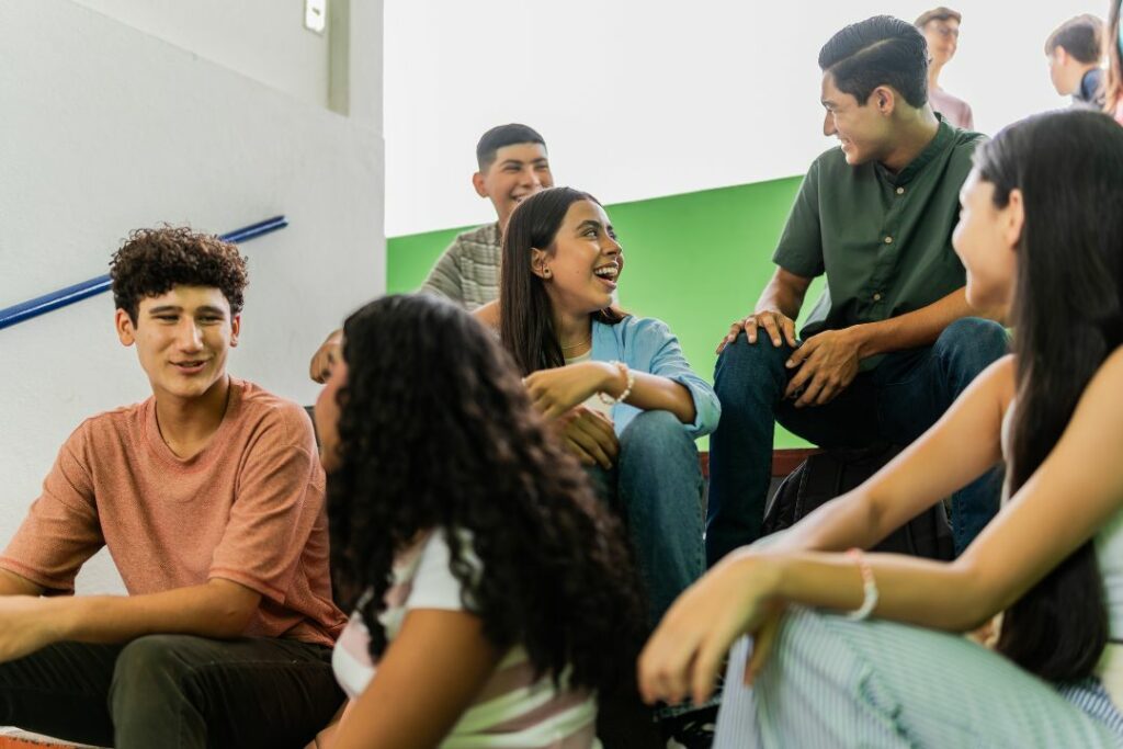 Des jeunes étudiants sont assis sur les marches d'un escalier et rigolent ensemble.