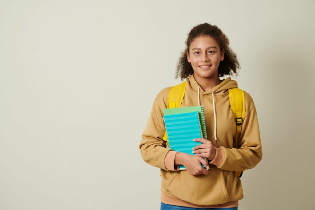 Une jeune fille qui tient un cahier bleu.
