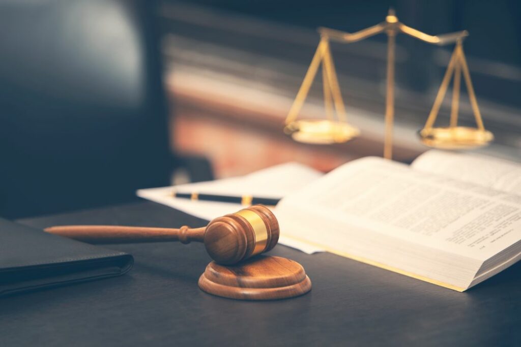 Un livre et un marteau posés sur une table noire avec une chaise de bureau.