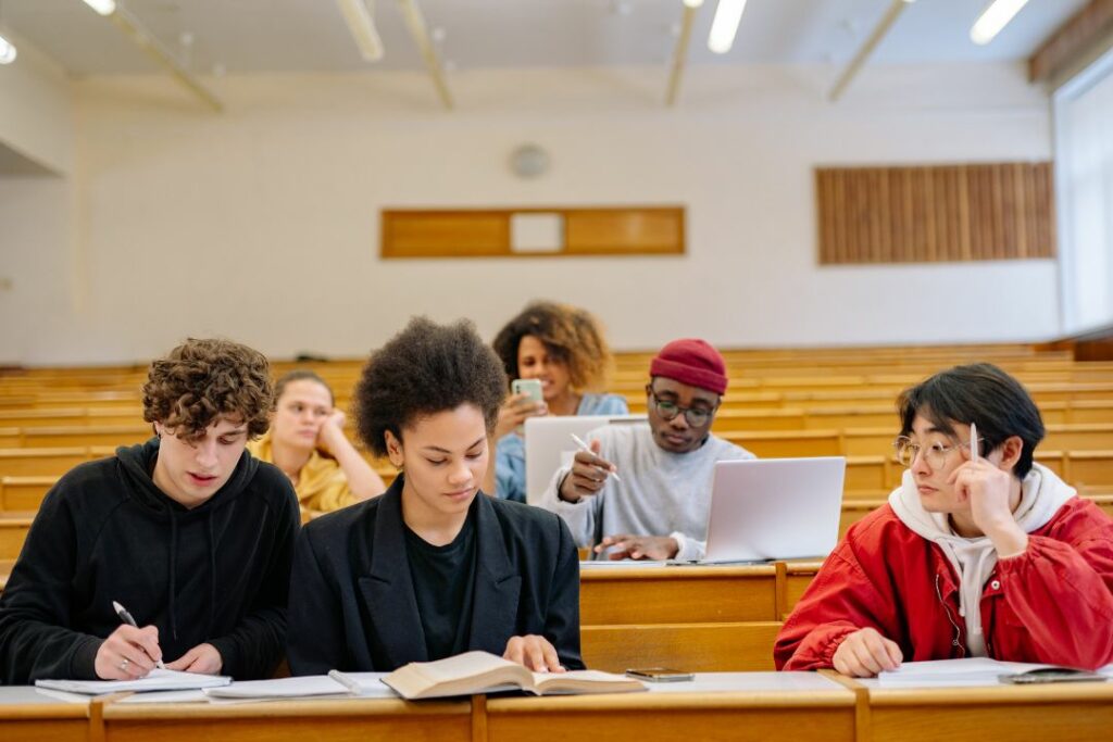 Groupe d'étudiants concentrés prenant des notes dans un amphithéâtre universitaire.