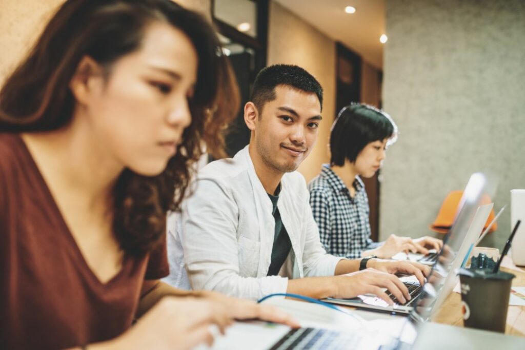 Jeunes stagiaires travaillant sur ordinateur dans un open space d'entreprise.